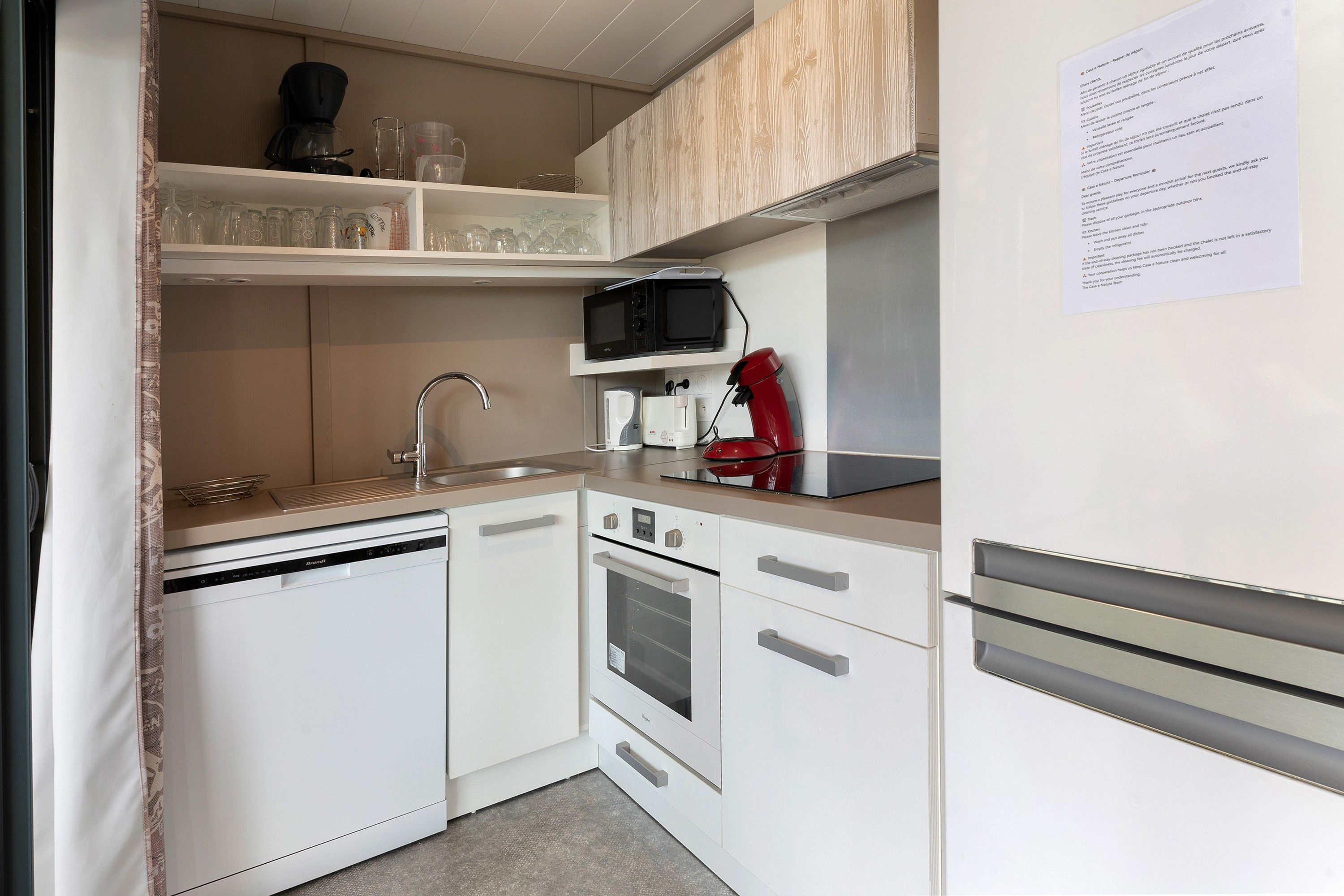 Una kitchenette compacta equipada con lavavajillas, horno, microondas y cafetera.