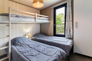 Ein Zimmer mit Etagenbetten, einem Nachttisch mit Lampe und einem Vorhangfenster.
