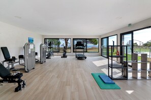 Un gimnasio con equipo de ejercicio, una cinta de correr y vistas al exterior.