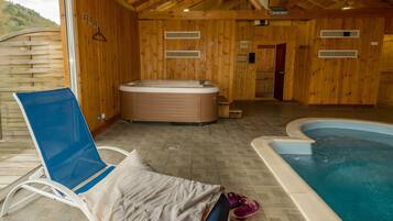 Ein Spa-Raum aus Holz mit Whirlpool, Schwimmbecken und Liegestuhl.