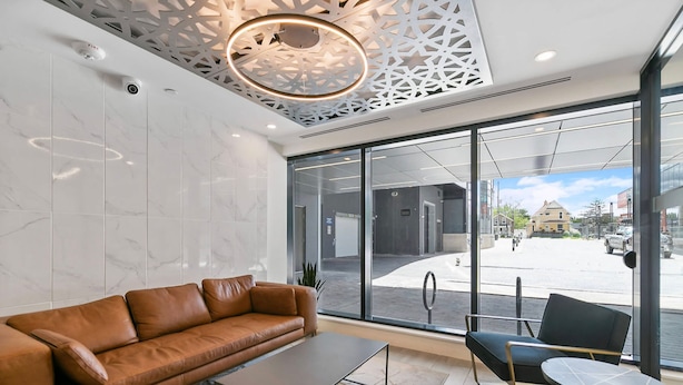 A modern lobby with a leather sofa, a coffee table, and a chair. - Modern High Rise Condo w Private Patio Downtown (Kitchener)