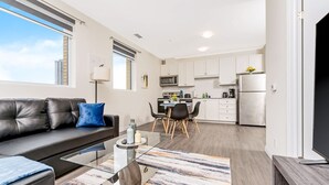 A modern apartment with a living room, dining area, and kitchen. - Modern High Rise Condo w Private Patio Downtown (Kitchener)