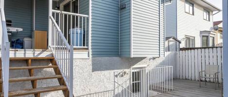 A residential property with a covered porch, wooden steps, a fenced backyard, and a chimney.