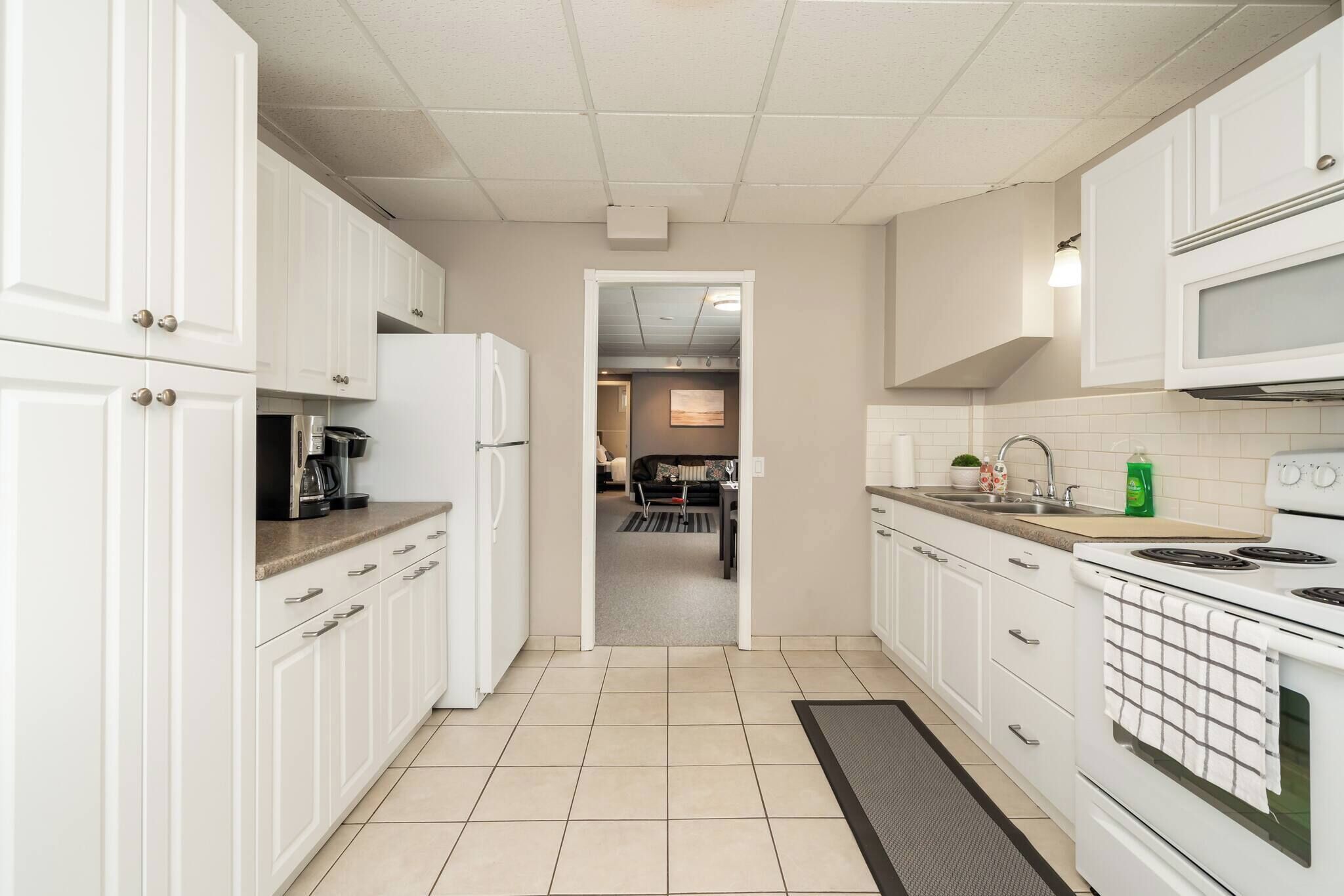 A kitchen with white cabinets, a microwave, a stove, and a sink.