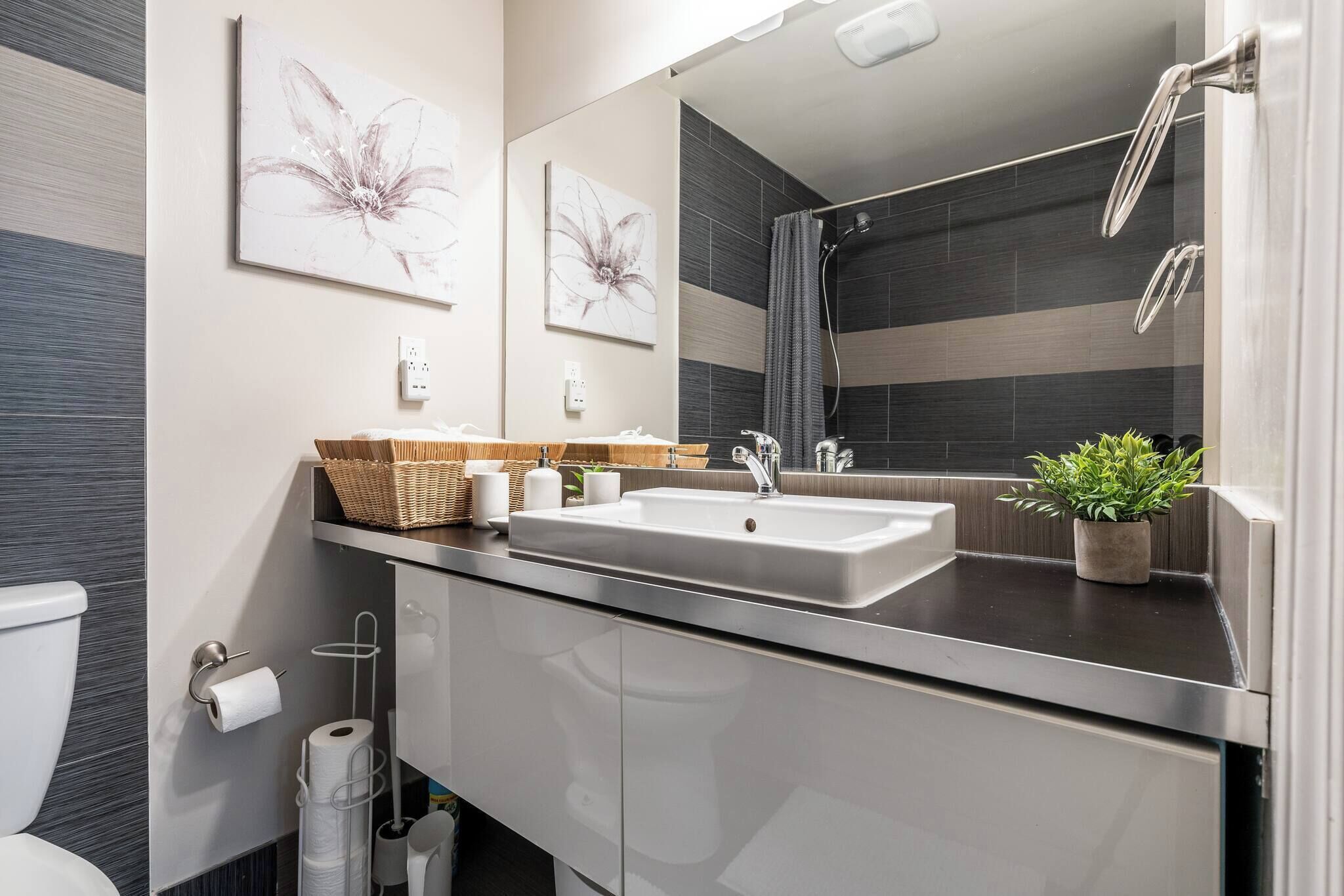 A modern bathroom with a sink, mirror, and toilet.