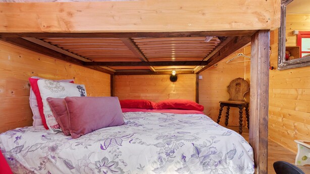 A wooden cabin room with a bunk bed, a wooden chair, and a mirror on the wall.