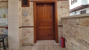A stone building with a wooden door, a fire extinguisher, and a small window.