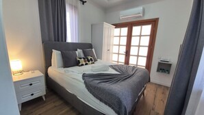 A bedroom with a bed, nightstand, and an air conditioning unit.