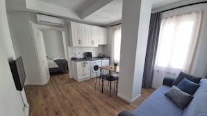 A modern apartment with a kitchenette, a dining area, and a living room with a sofa.