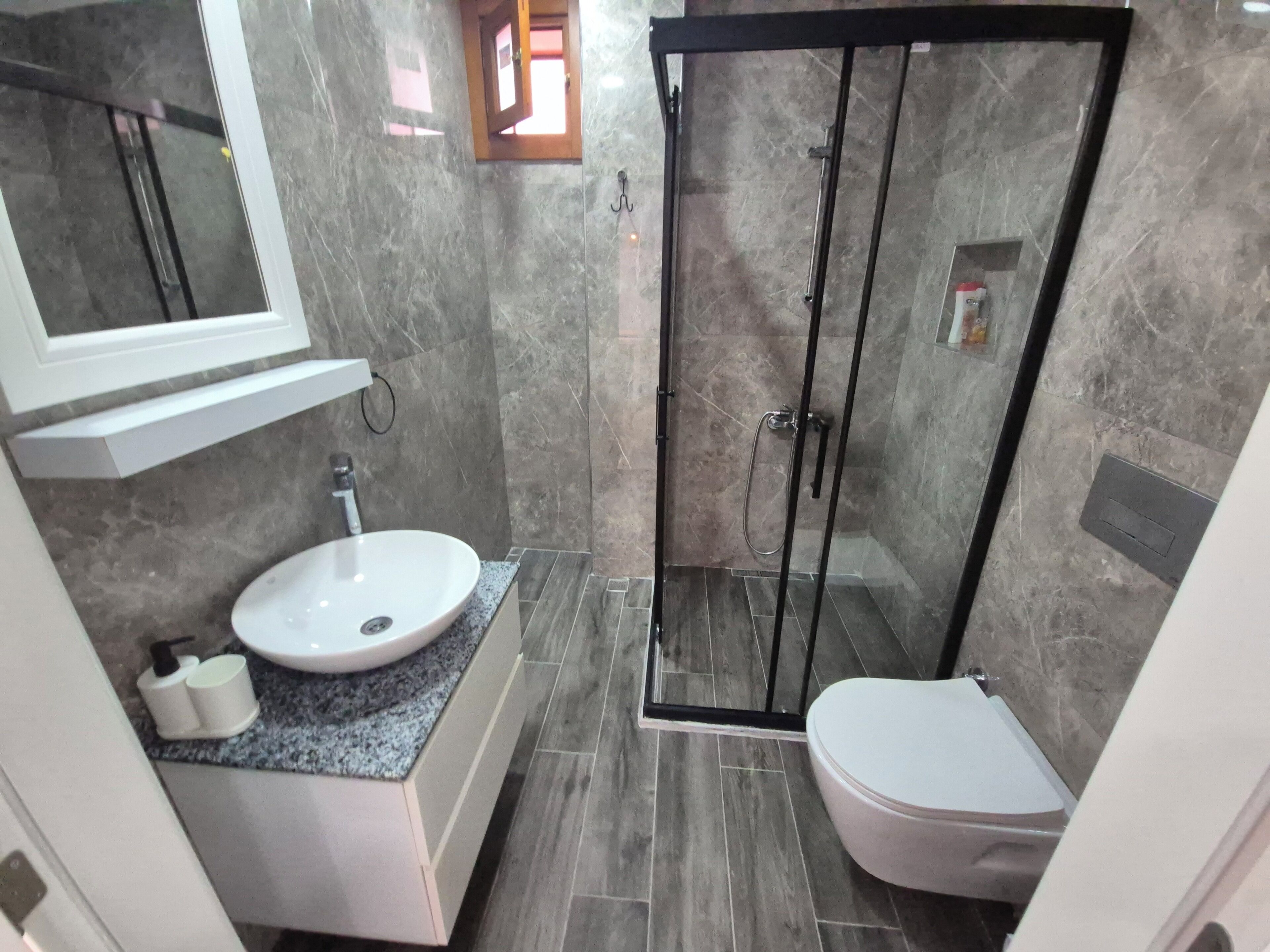 A bathroom with a sink, toilet, and glass-enclosed shower.