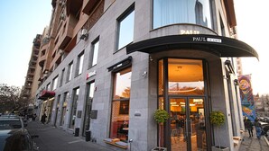 A building with a curved entrance, a sign for 'Paul Le Cafe', and a visible storefront with a red awning. - Modern Studio Apartment in the City Centre (Yerevan)