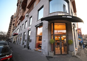 A building with a curved entrance, a sign for 'Paul Le Cafe', and a visible storefront with a red awning. - Modern Studio Apartment in the City Centre (Yerevan)