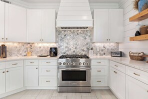 Et moderne køkken med hvide skabe, en stålkomfur og en backsplash med hexagonfliser.