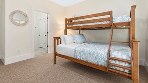 A bunk bed with a wooden frame and patterned bedding, a round mirror on the wall, and a door leading to another room. - Lake Lyfe Oconee - Game Room, Dock, Firepit (Eatonton)
