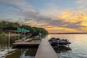 A wooden dock extending into calm water with boats docked on the right. - Lake Lyfe Oconee - Game Room, Dock, Firepit (Eatonton)