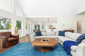 A spacious living room with a large sectional sofa, a wooden coffee table, and a blue rug. - Lake Lyfe Oconee - Game Room, Dock, Firepit (Eatonton)