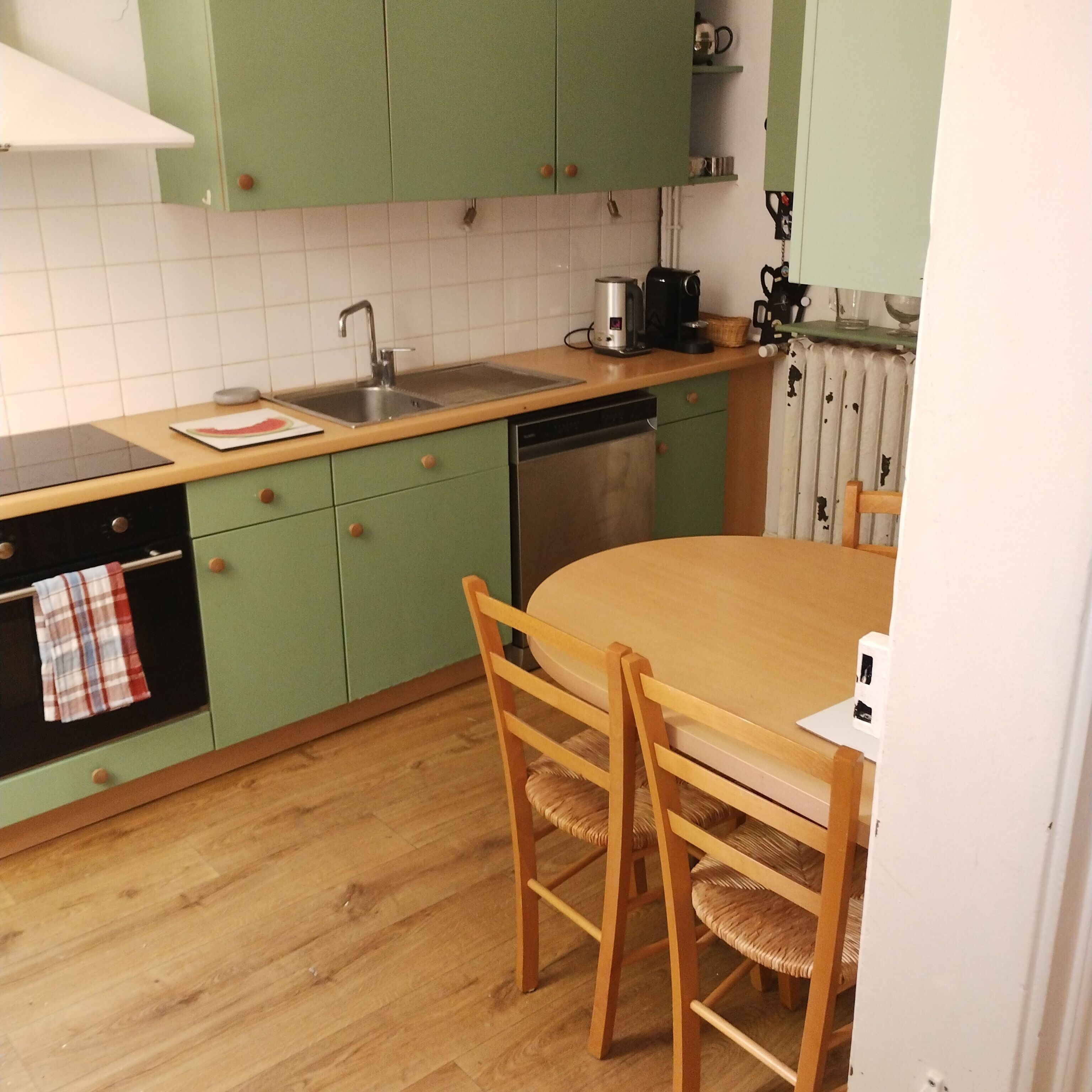 A kitchen with green cabinets, a wooden table, and a sink.