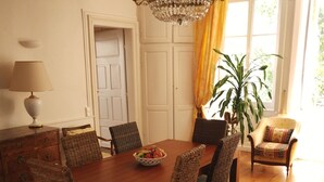 Een eetruimte met een houten tafel, rieten stoelen, een kroonluchter en een plant in pot.