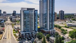 Två höga byggnader med modern arkitektur, omgivna av en stadsbild.