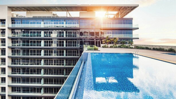A modern building with a rooftop pool and a clear view of the sunset. - Bloomfields Studio in Park View   (Abu Dhabi)