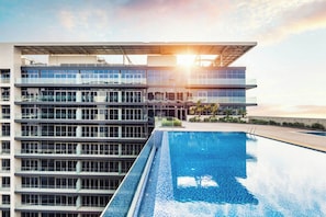Ein modernes Gebäude mit Pool auf dem Dach und freiem Blick auf den Sonnenuntergang.