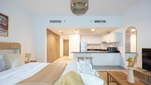 A modern hotel room with a bed, bedside table, lamp, and a view into the kitchen area. - Bloomfields Studio in Park View   (Abu Dhabi)