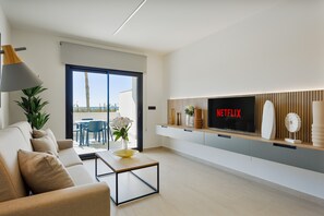 A modern living room with a sofa, coffee table, and a flat-screen TV mounted on the wall. - Oasis Laguna Resort Pool & View Superior II (Guardamar)
