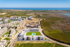 An aerial view of a coastal residential area with modern apartment buildings, a swimming pool, and a beach. - Oasis Laguna Resort Pool & View Superior II (Guardamar)