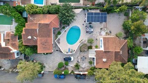 Vista aerea di una zona residenziale con piscina, pannelli solari e un piccolo parcheggio.