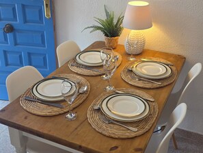 Ett matbord dukat med tallrikar, bestick och glas, tillsammans med en lampa och en krukväxt.