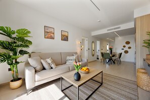 A modern living room with a sofa, coffee table, and potted plants. - Oasis Laguna Resort Pool & View Premium III (Guardamar)