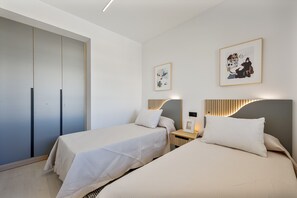 Ein modernes Schlafzimmer mit zwei Betten, einem Kleiderschrank und Bildern an den Wänden.