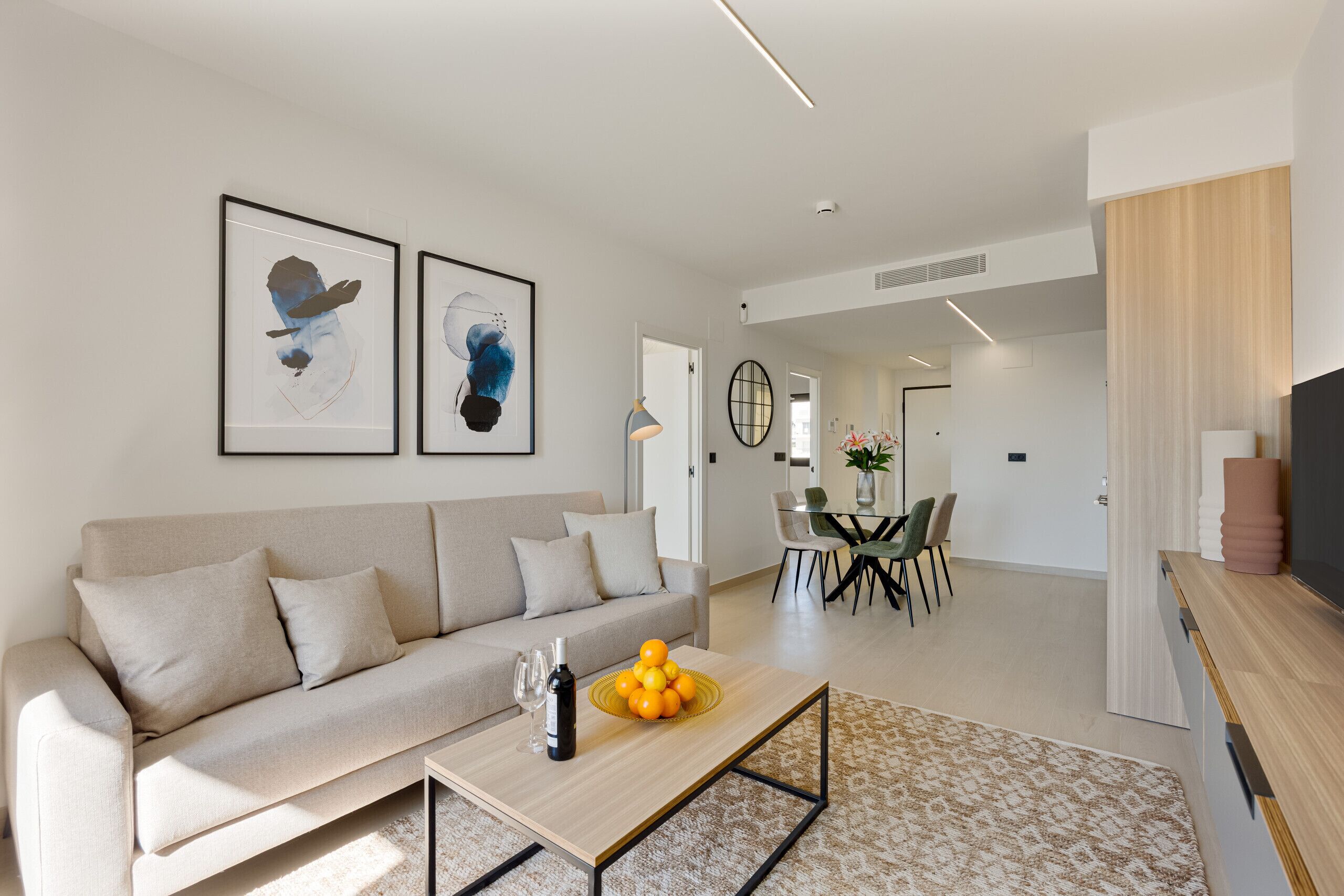 Un salon moderne avec un canapé, une table basse et des œuvres d’art accrochées au mur.