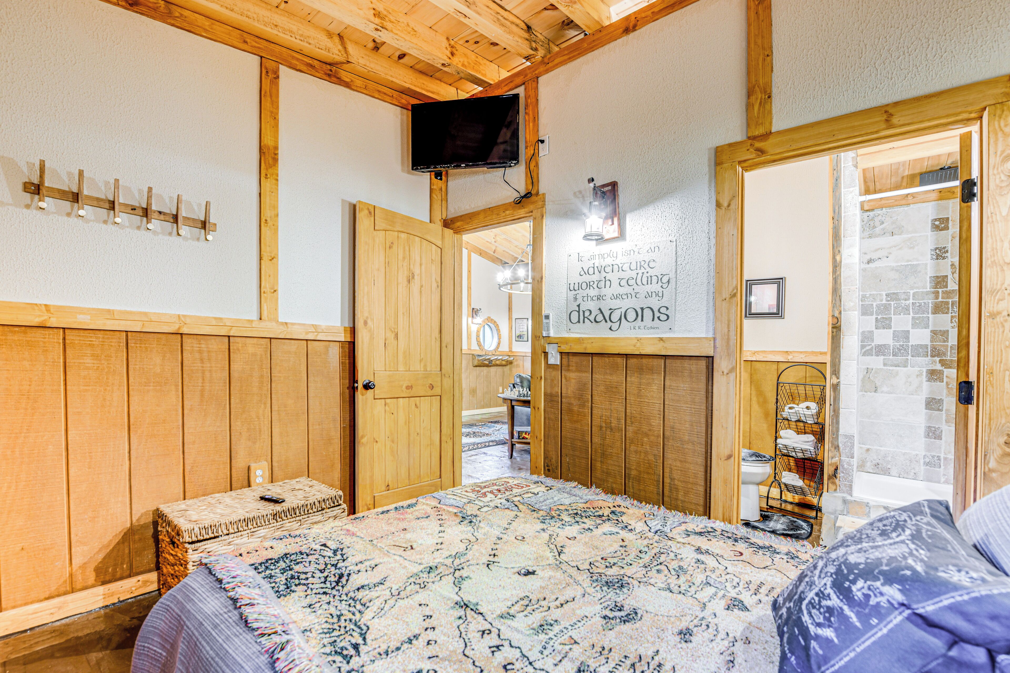 A wooden room with a bed, a television mounted on the wall, and a sign with a quote.