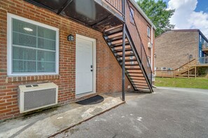 A brick building with a white door, a window, and a metal staircase leading to a second floor. - 6 Mi to Dtwn & UT! Quaint Apartment in Knoxville (Knoxville)