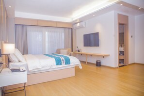Habitación de hotel moderna con una cama grande, mesita de noche, lámpara y un televisor de pantalla plana montado en la pared.