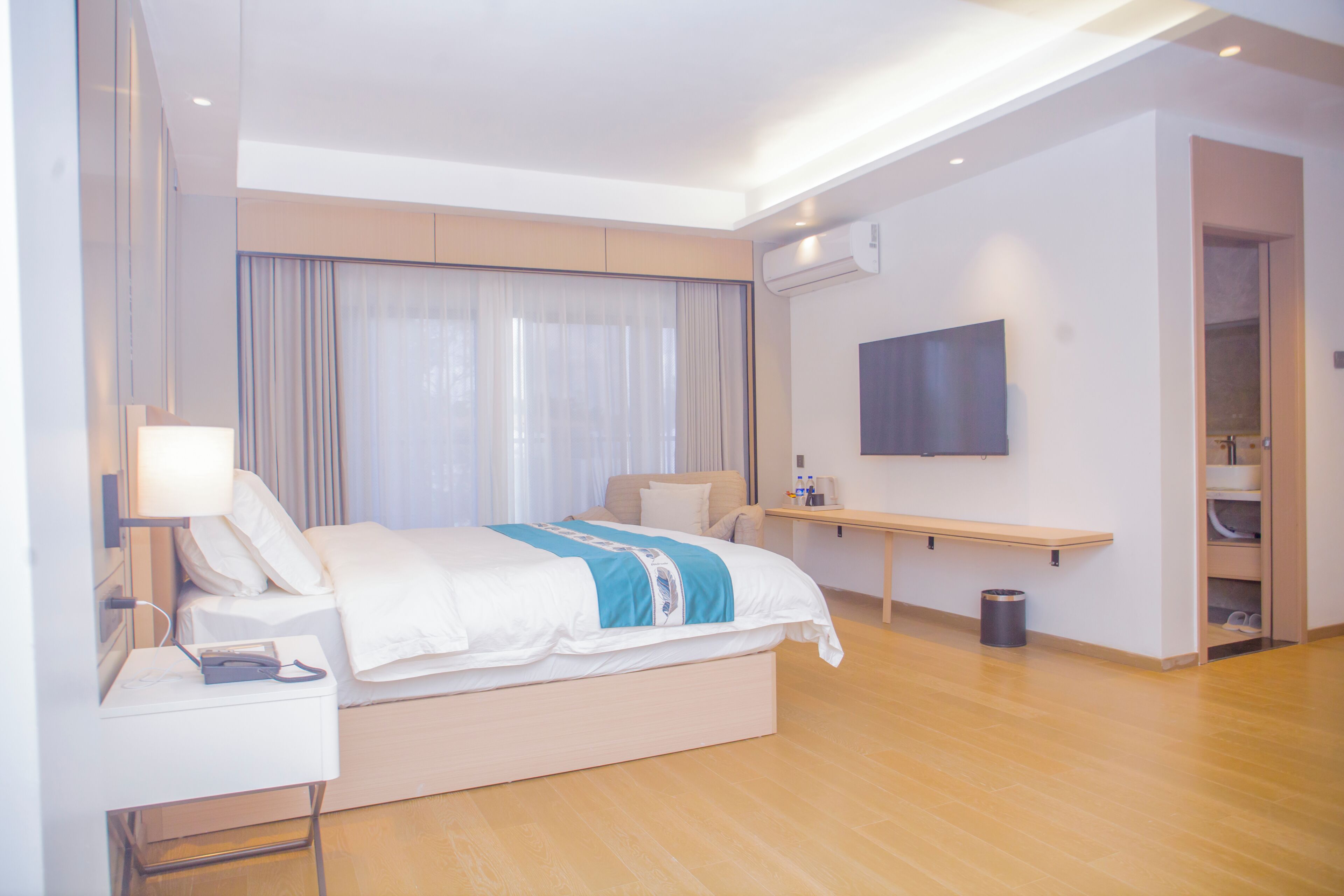 Une chambre d’hôtel moderne équipée d’un lit, d’une table de chevet, d’une lampe et d’un téléviseur fixé au mur.