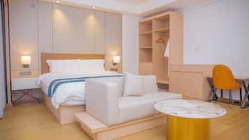 Una habitación de hotel moderna con cama, sofá, una pequeña mesa, escritorio y una silla.