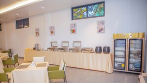 Un salón de conferencias con mesas, sillas, mesas de buffet y un refrigerador.