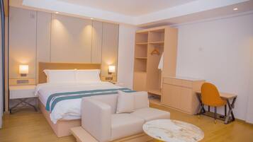 A modern hotel room with a bed, a sofa, a desk, and a wardrobe.