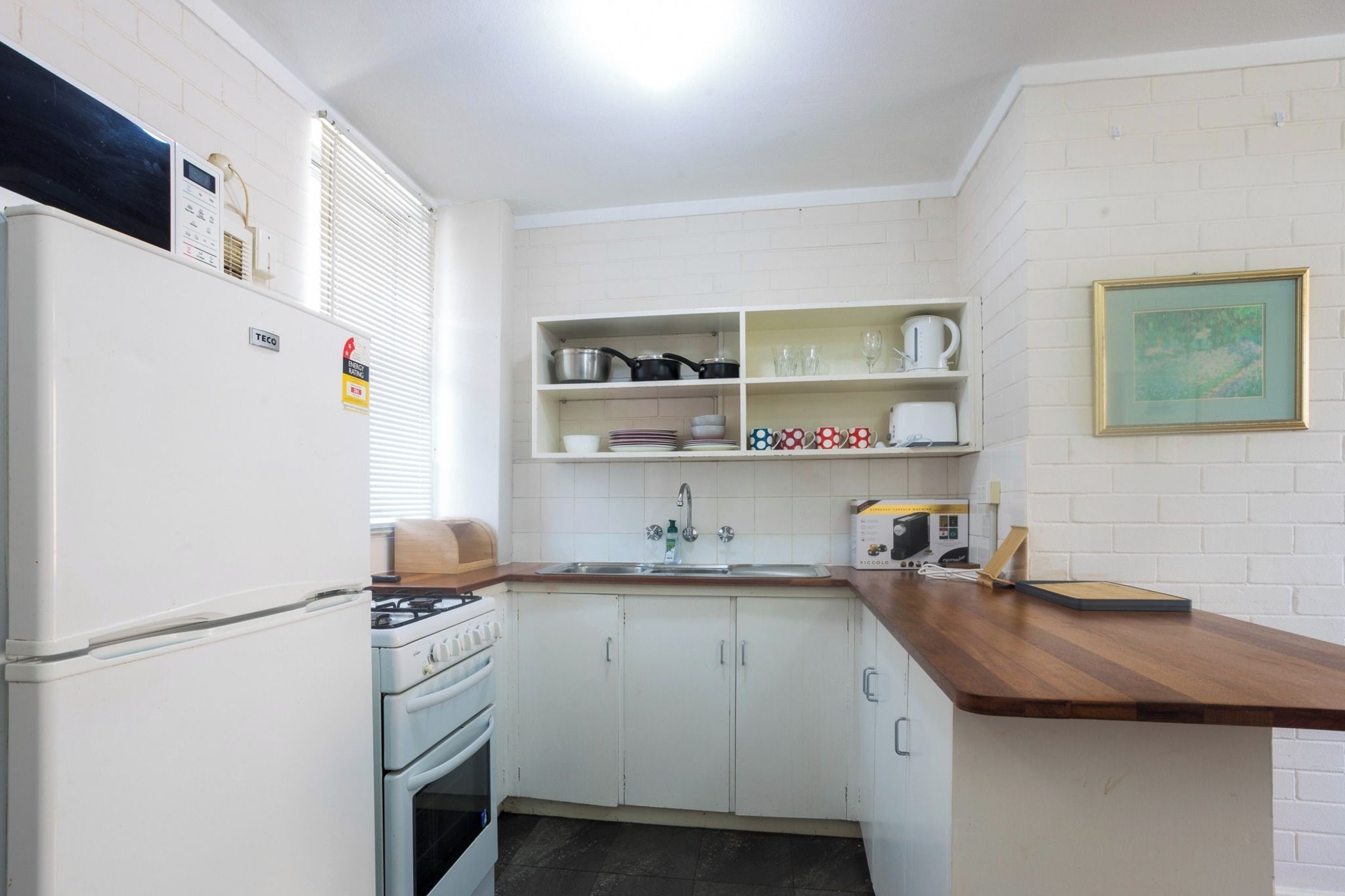 A compact kitchen with white cabinets, a stove, a sink, and a countertop.
