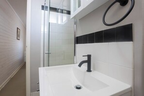 A bathroom with a white sink, a glass shower enclosure, and a black towel ring on the wall. - Lovely 1 BDR in the heart of Fremantle w Parking (Fremantle)