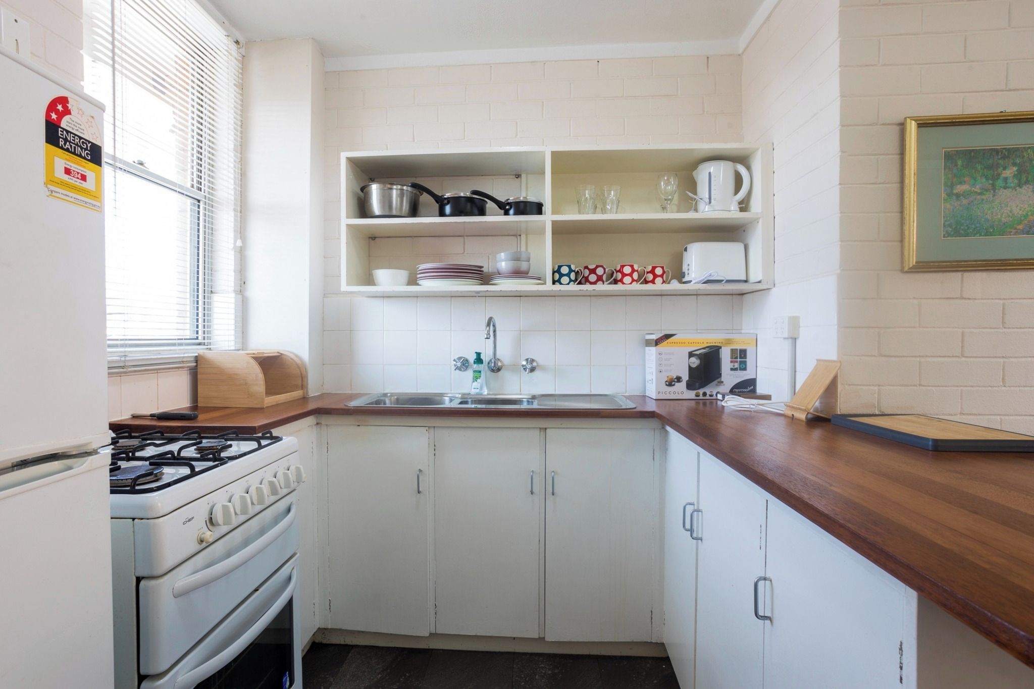 A compact kitchen with white cabinets, a gas stove, a sink, and a countertop.