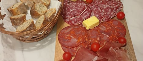Une planche de charcuterie avec différentes sortes de viandes, de fromages et de cornichons, posée sur une table en marbre.