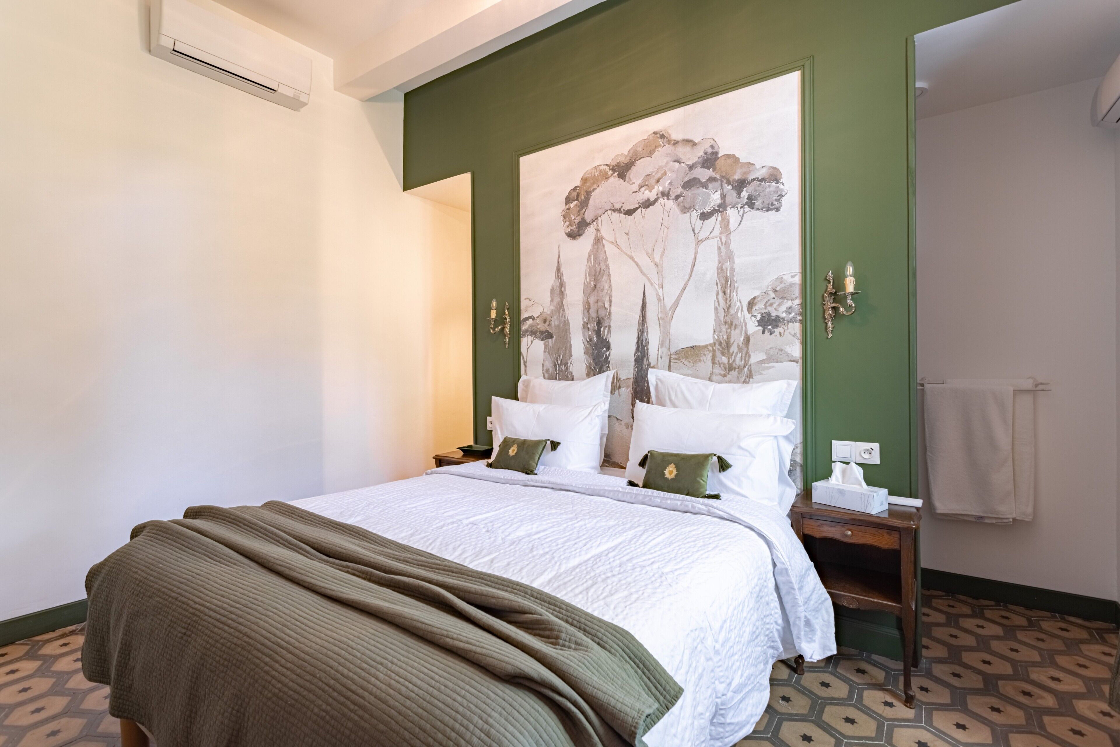 Ein Hotelzimmer mit einem Bett, einem Nachttisch, einem Bild an der Wand und einer grünen Akzentwand.