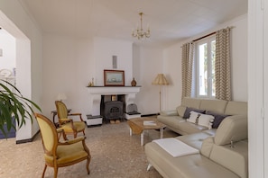 A living room with a sofa, chairs, a fireplace, a chandelier, and a window with curtains.