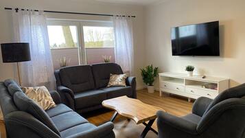 Un soggiorno moderno con un divano, un tavolino, una TV e una console bianca.