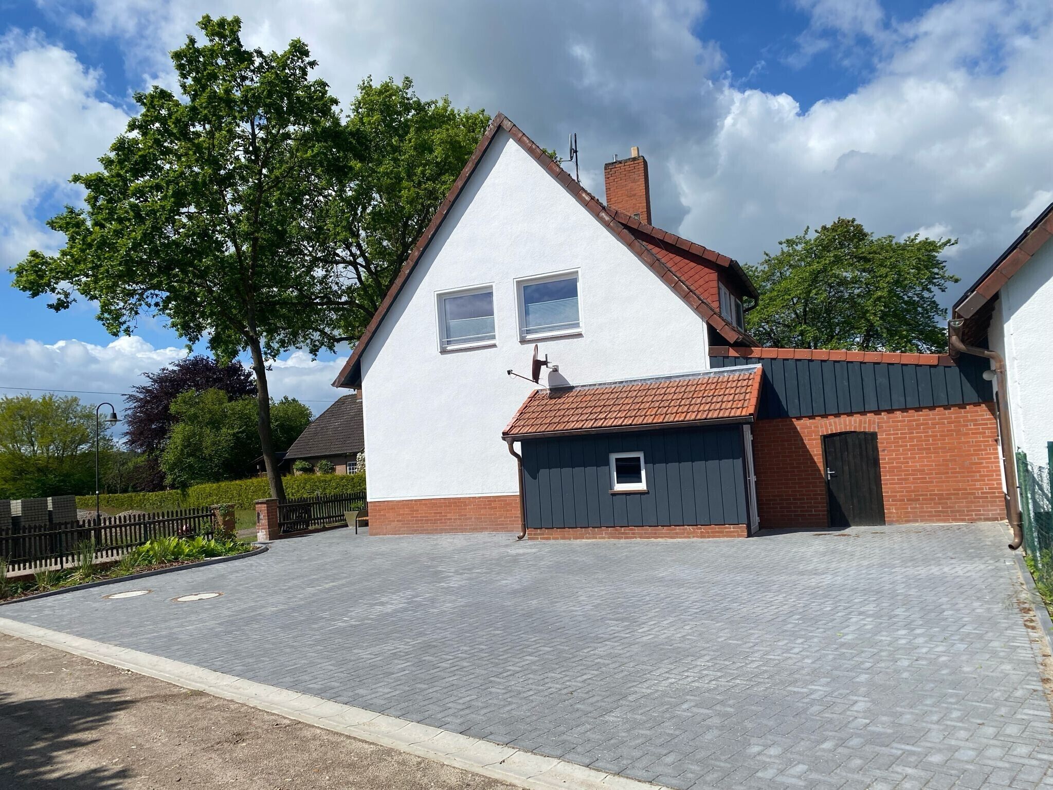 A two-story house with a paved driveway, a small attached garage, and a brick chimney.