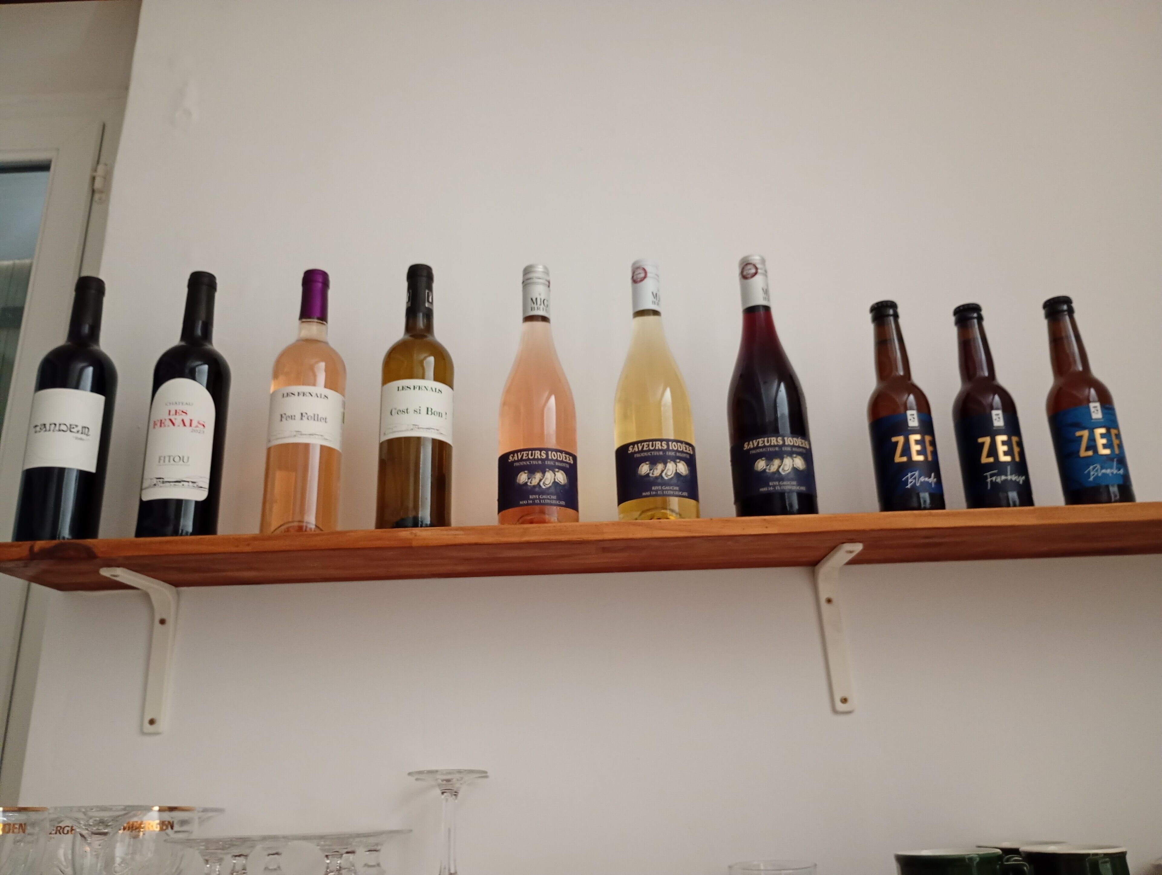 A wooden shelf with various wine bottles.