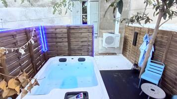 Ein Whirlpool mit Bedienfeld, umgeben von Holzwänden und einem kleinen Tisch mit einem Stuhl.